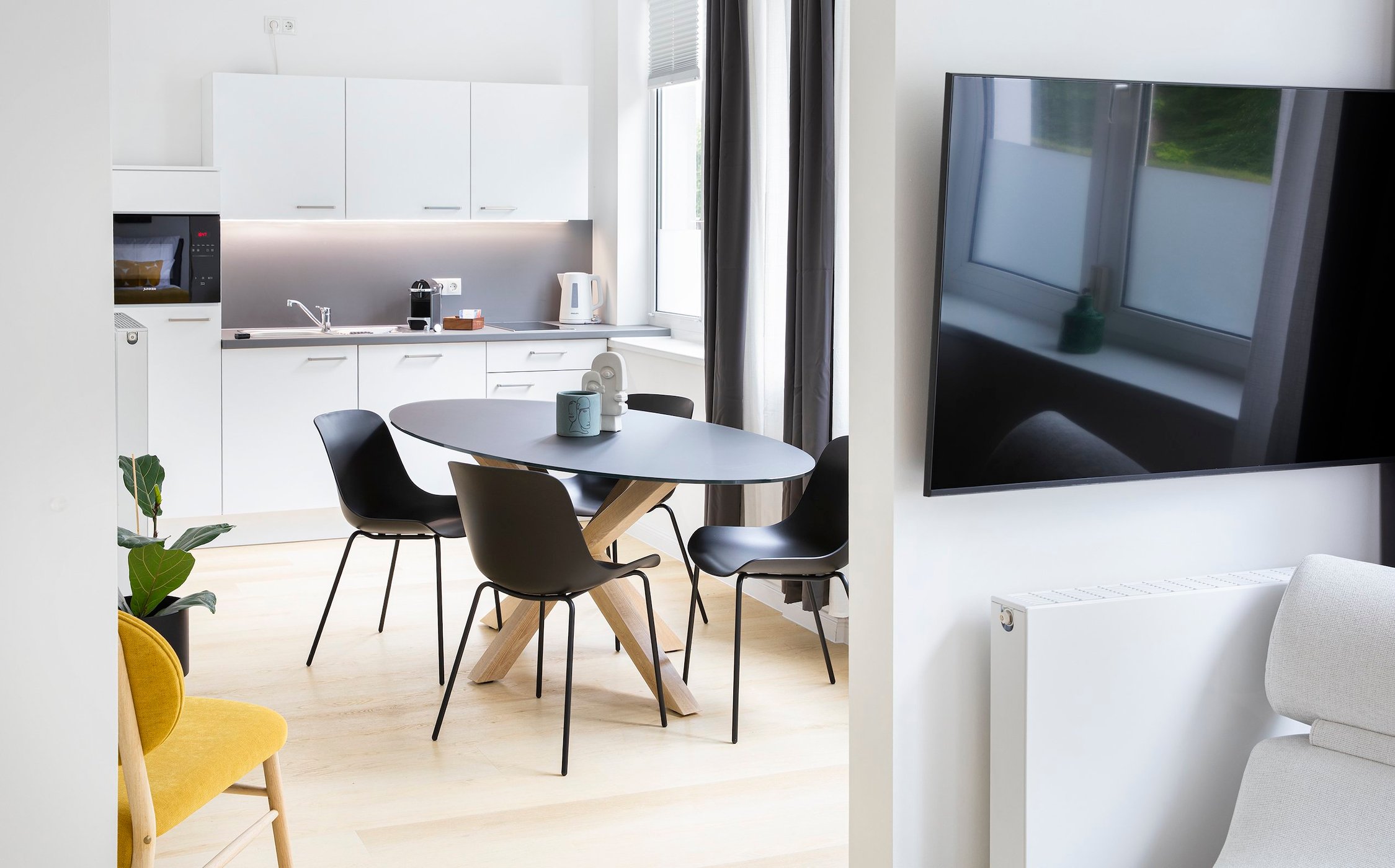 Moderne Küche und Essbereich in Weiß und Grau, mit dunklem Tisch und Stühlen