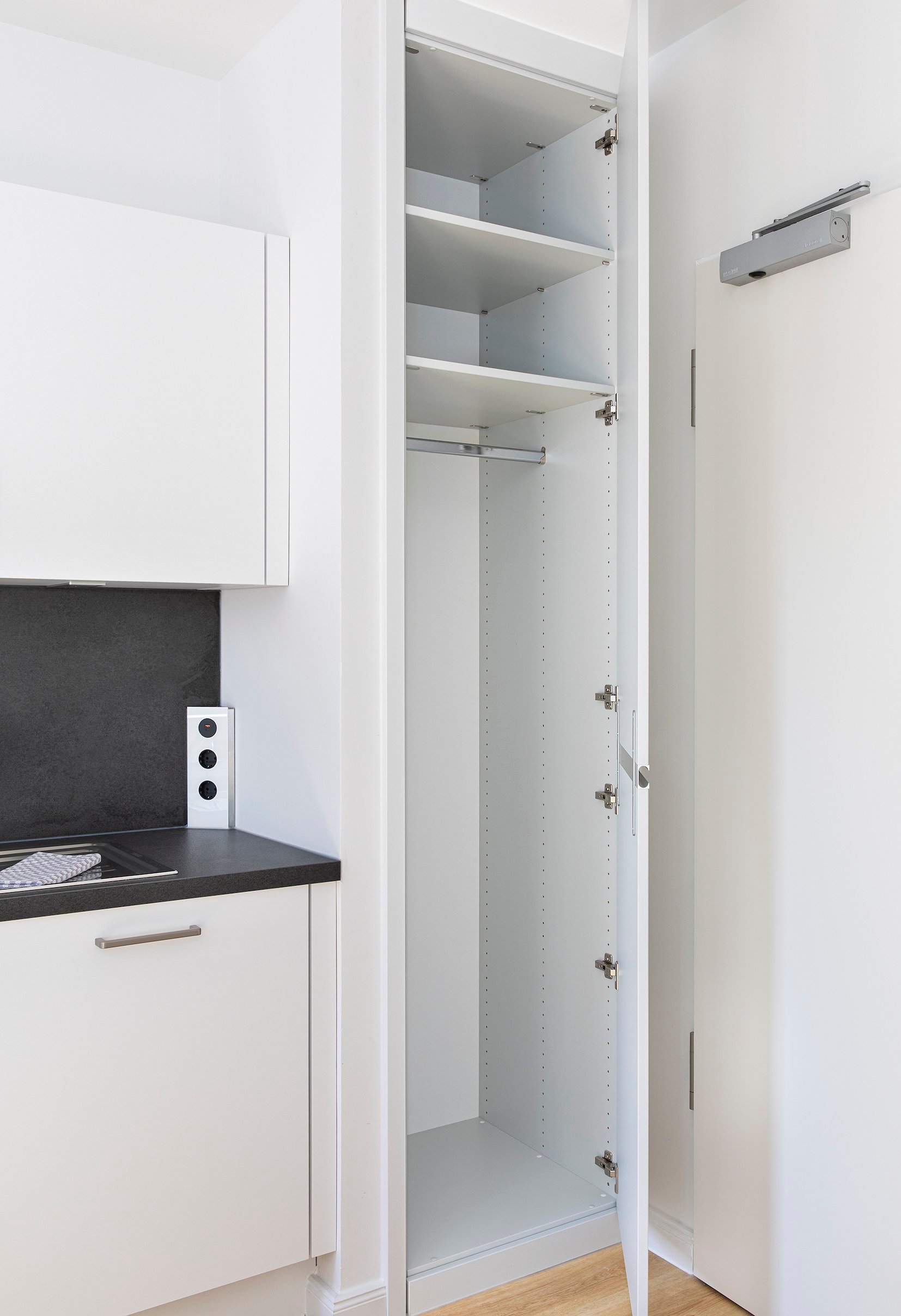 Offener weißer Hochschrank neben Miniküche, drei Regalböden, Kleiderstange