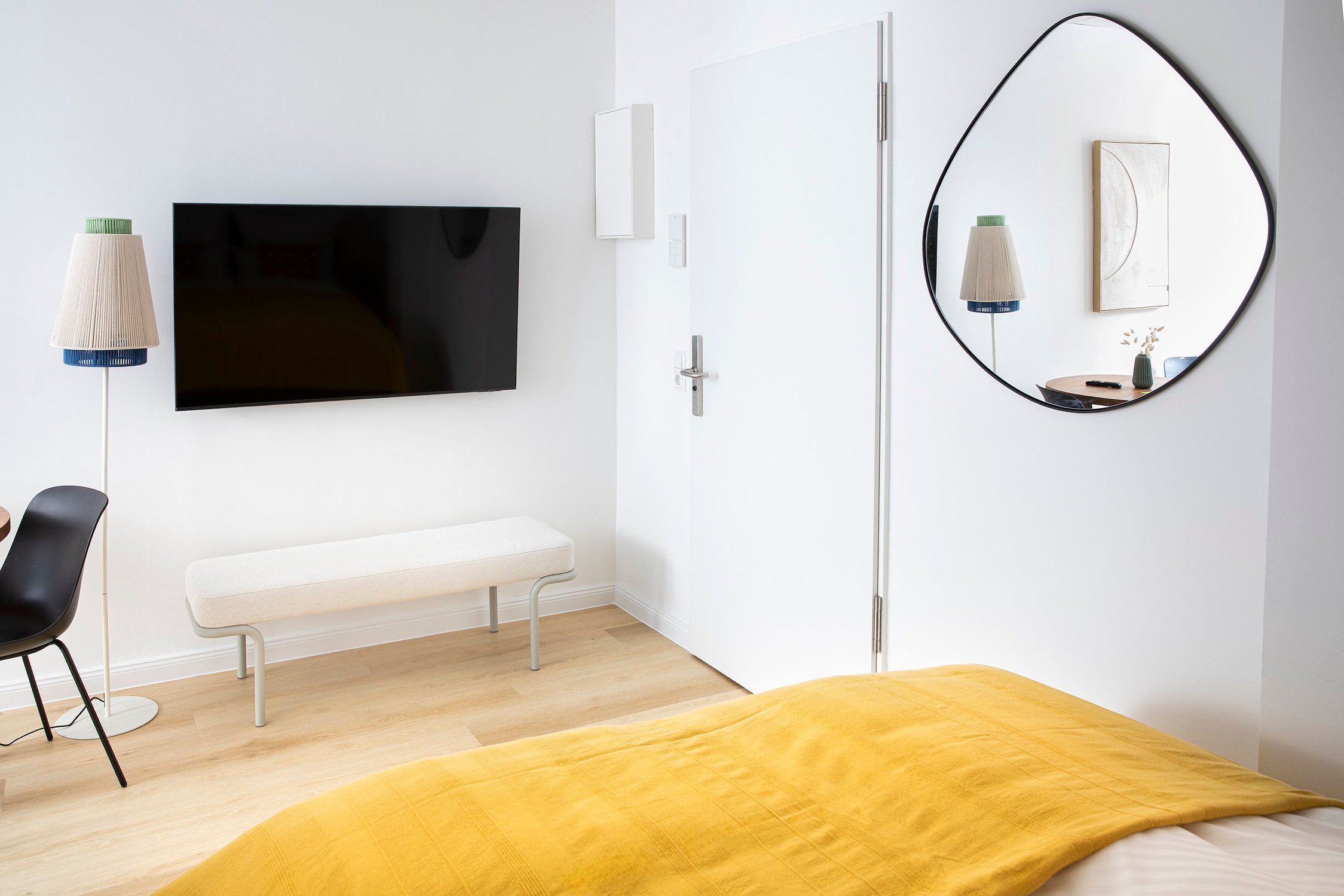 Schlafzimmer mit gelber Decke, dunklem Fernseher und spiegelnder Wanddekoration