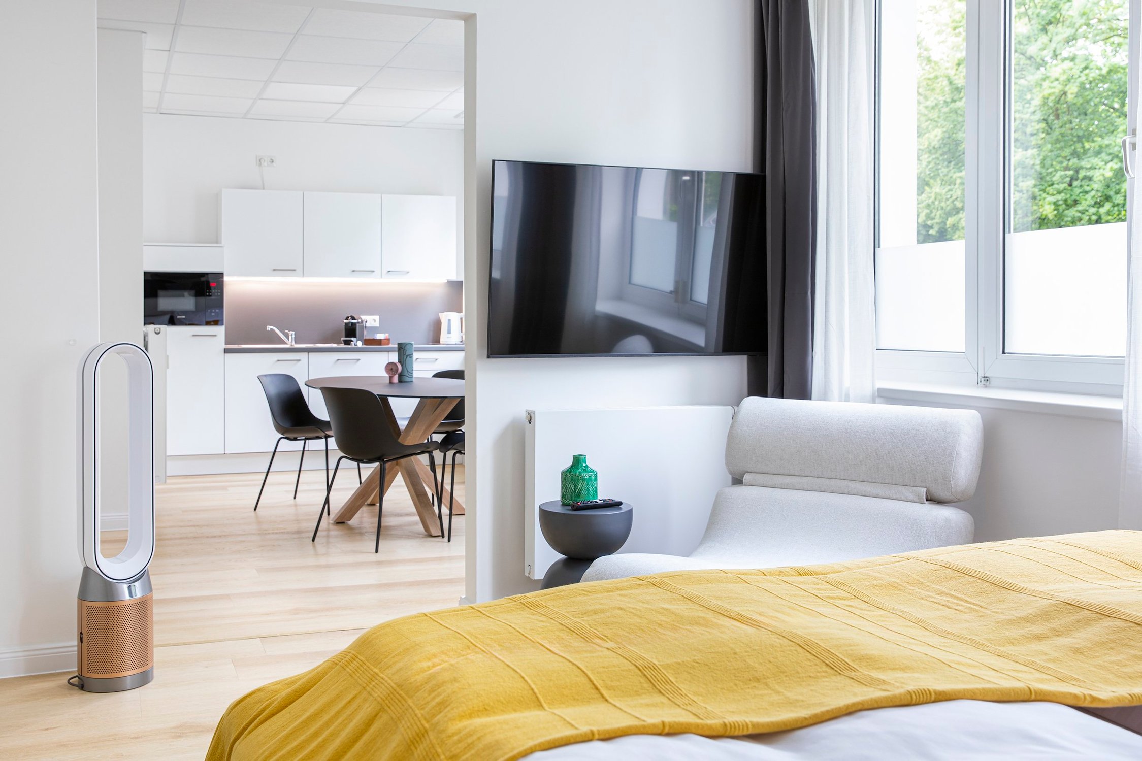 Modernes Studio-Apartment mit Küchenzeile, Esstisch, Sofa und Fernseher, holzfarbener Fußboden