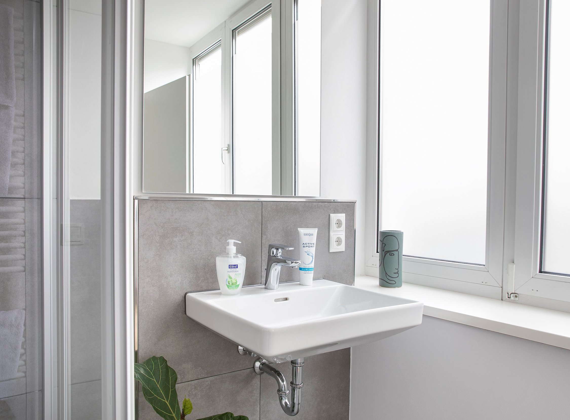 Modernes Badezimmer mit rechteckigem Waschbecken, Spiegel und großem Fenster
