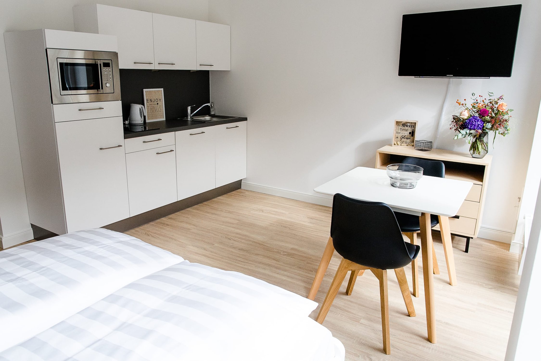 Modernes Studio-Apartment mit Küchenzeile in Weiß, Mikrofon, Esstisch für zwei Personen