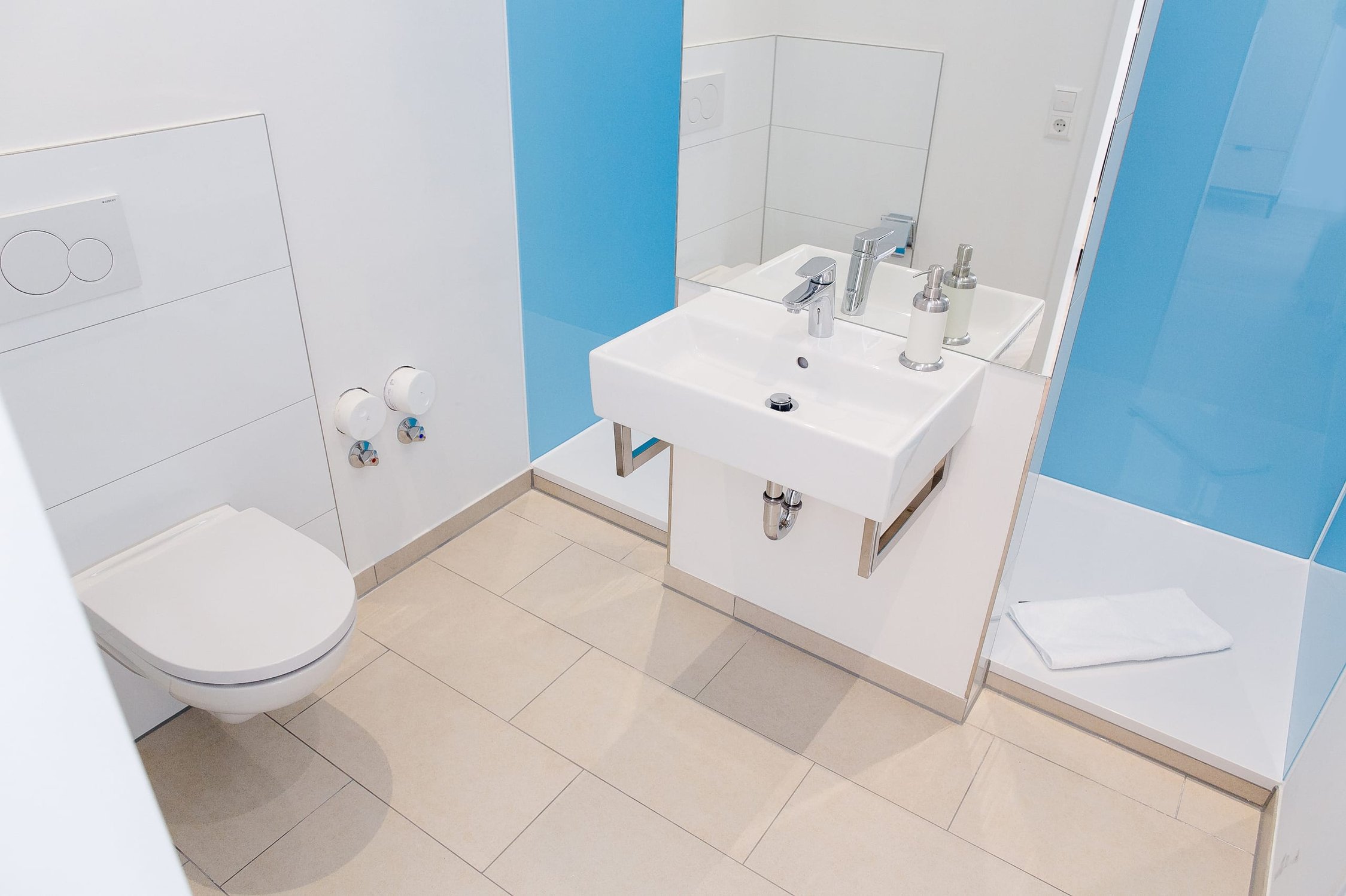 Modernes Bad mit weißer Toilette, Waschbecken, Spiegel und blauer Wand