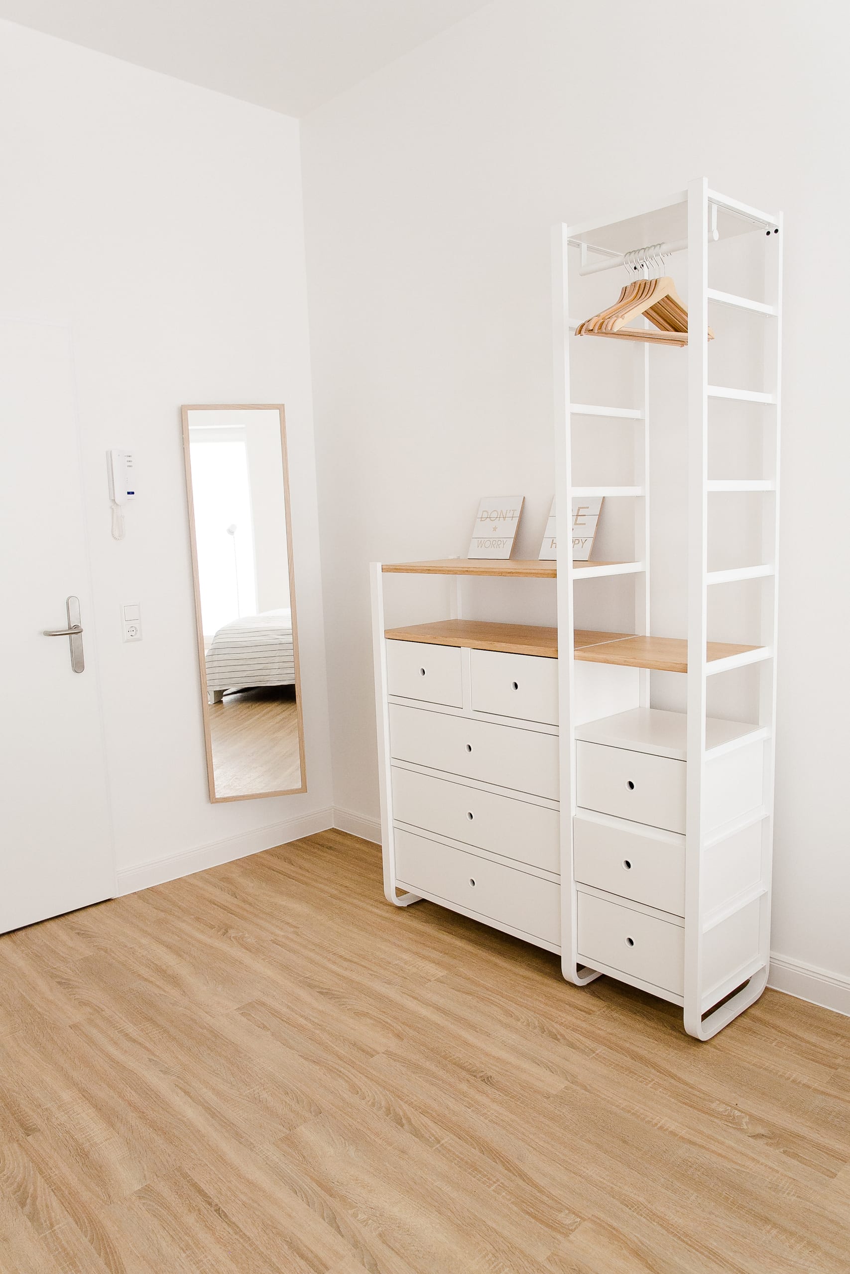Zimmer mit weißem Schrank, Holzboden und Spiegel, reflektiertes Bett