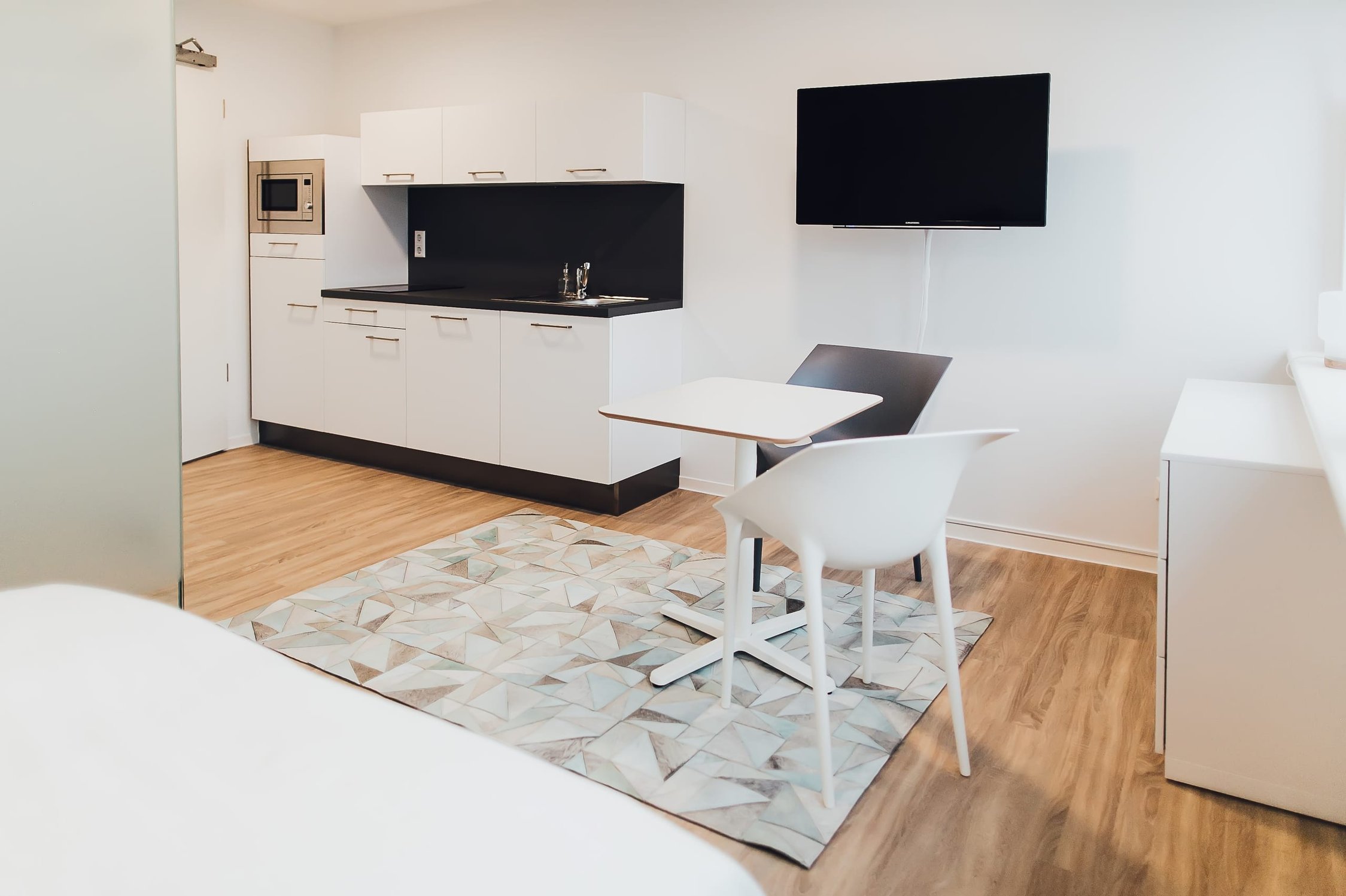 Helles Studio-Apartment mit weißer Küchenzeile, Esstisch für zwei Personen und Fernseher