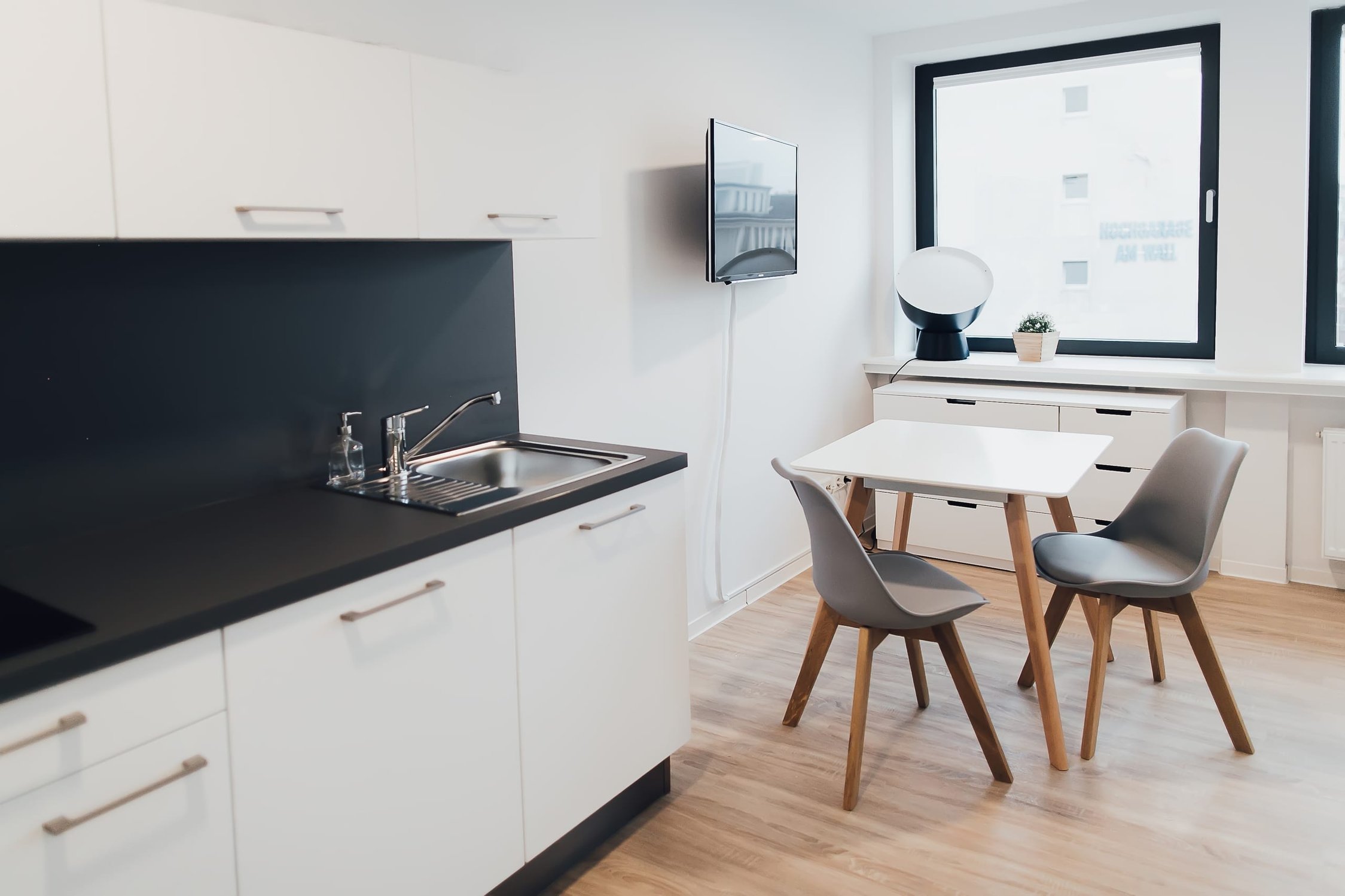 Moderne Küche mit schwarzer Arbeitsplatte, weißen Schränken und Essbereich