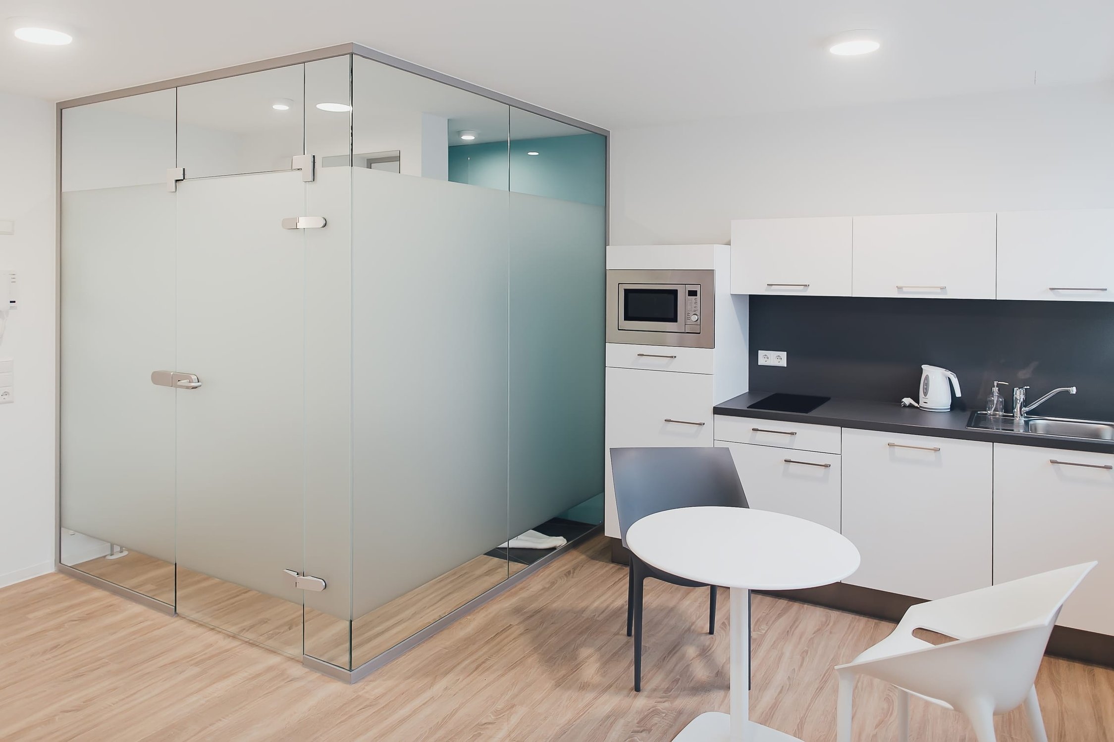 Modernes Apartment mit Glaswand, kleiner Küche und Esstisch für zwei Personen