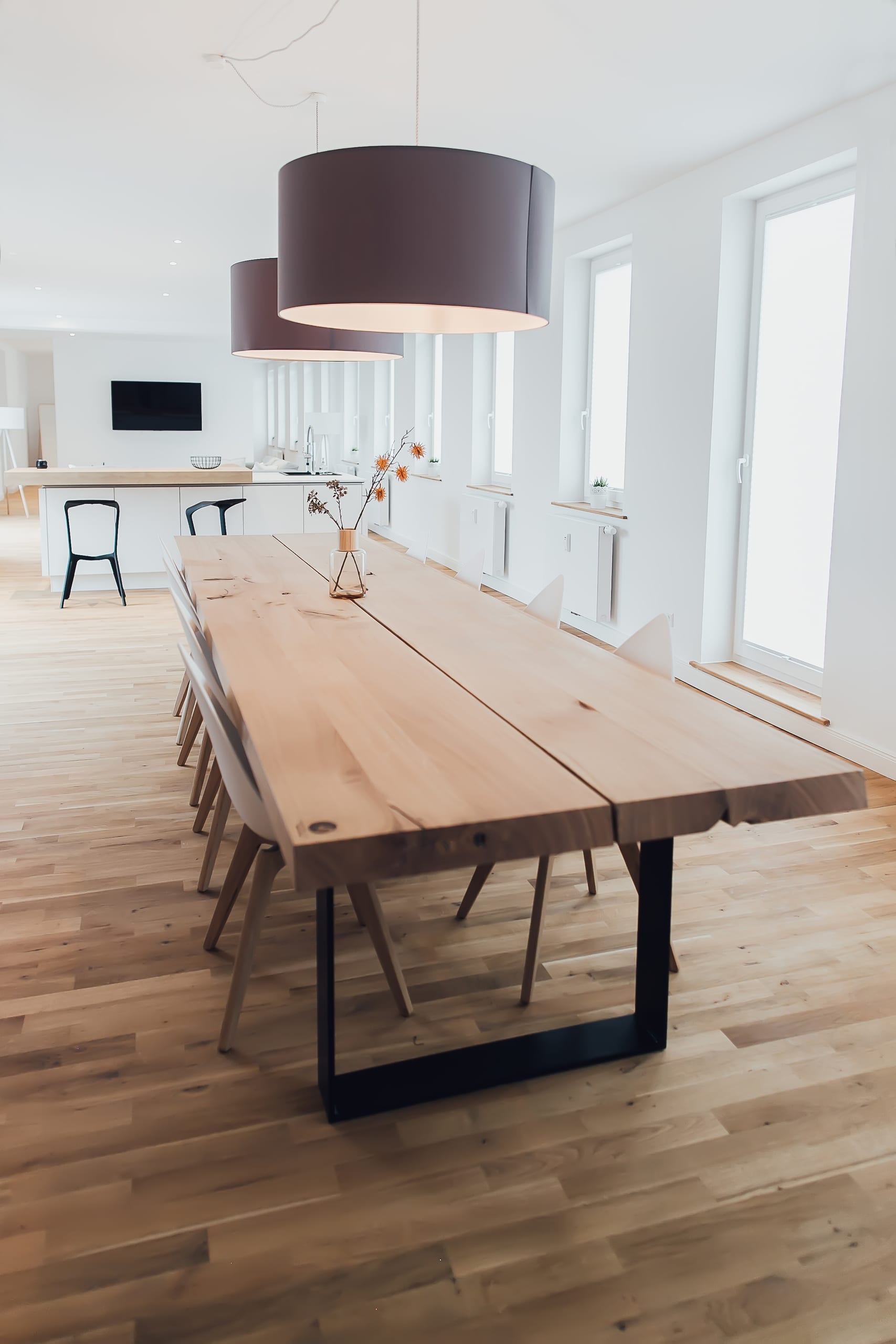 Modernes Esszimmer mit langem Holz-Tisch, sechs Stühlen und zwei runden Pendelleuchten