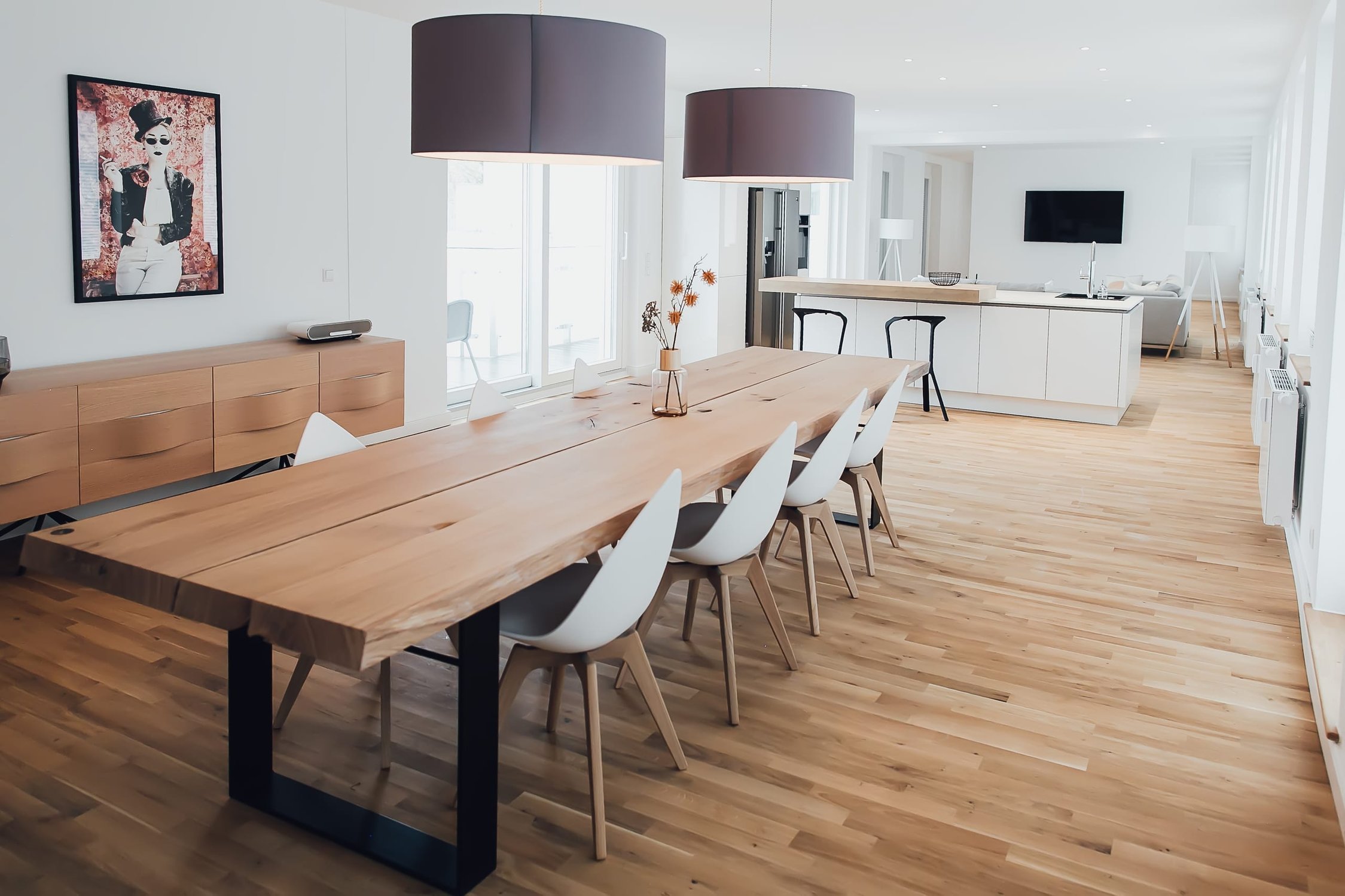 Geräumiges Esszimmer mit modernem Holztisch, weißen Stühlen und zwei großen Pendelleuchten