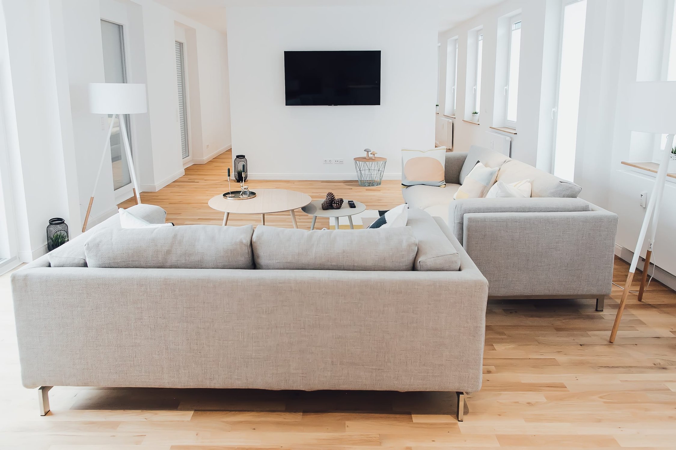 Helles Wohnzimmer mit Ecksofa, TV-Gerät und Holzboden