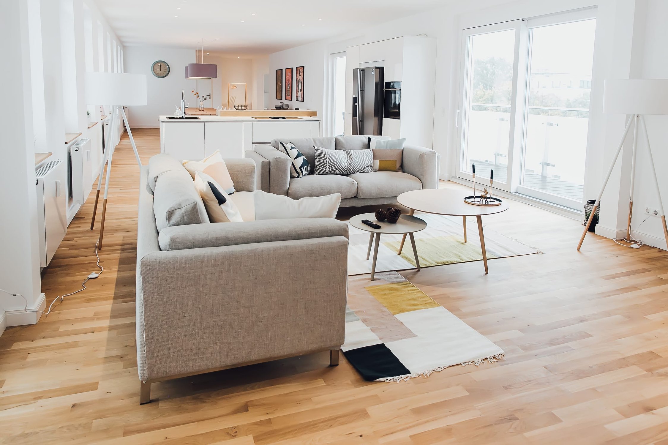 Modernes Wohnzimmer mit heller Holzboden, grauen Sofas und bunten Teppichen