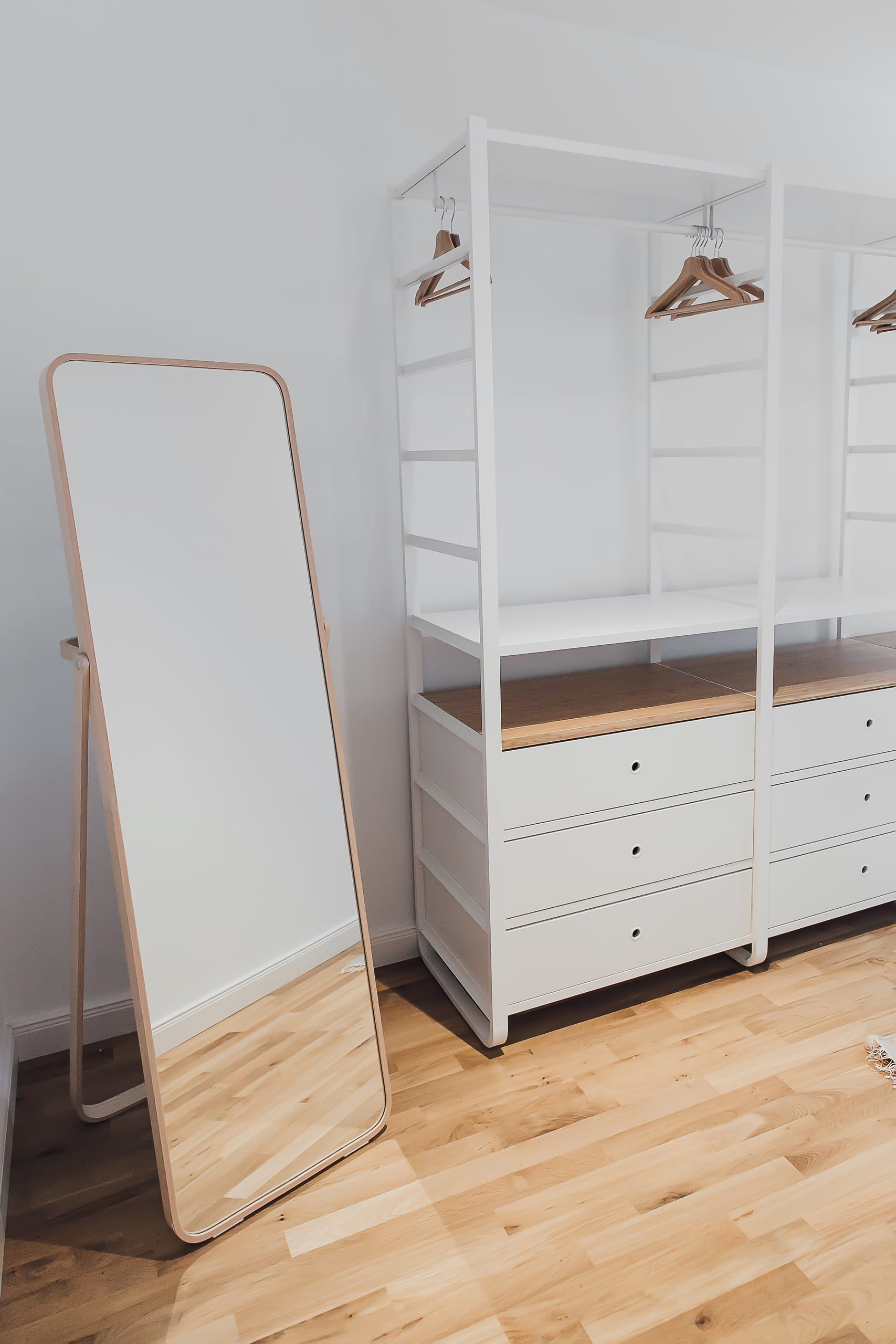 Möbel Schlafzimmer, Ganzkörperspiegel mit Holzrahmen, weißer Kleiderschrank mit Holzschubladen, heller Holzboden