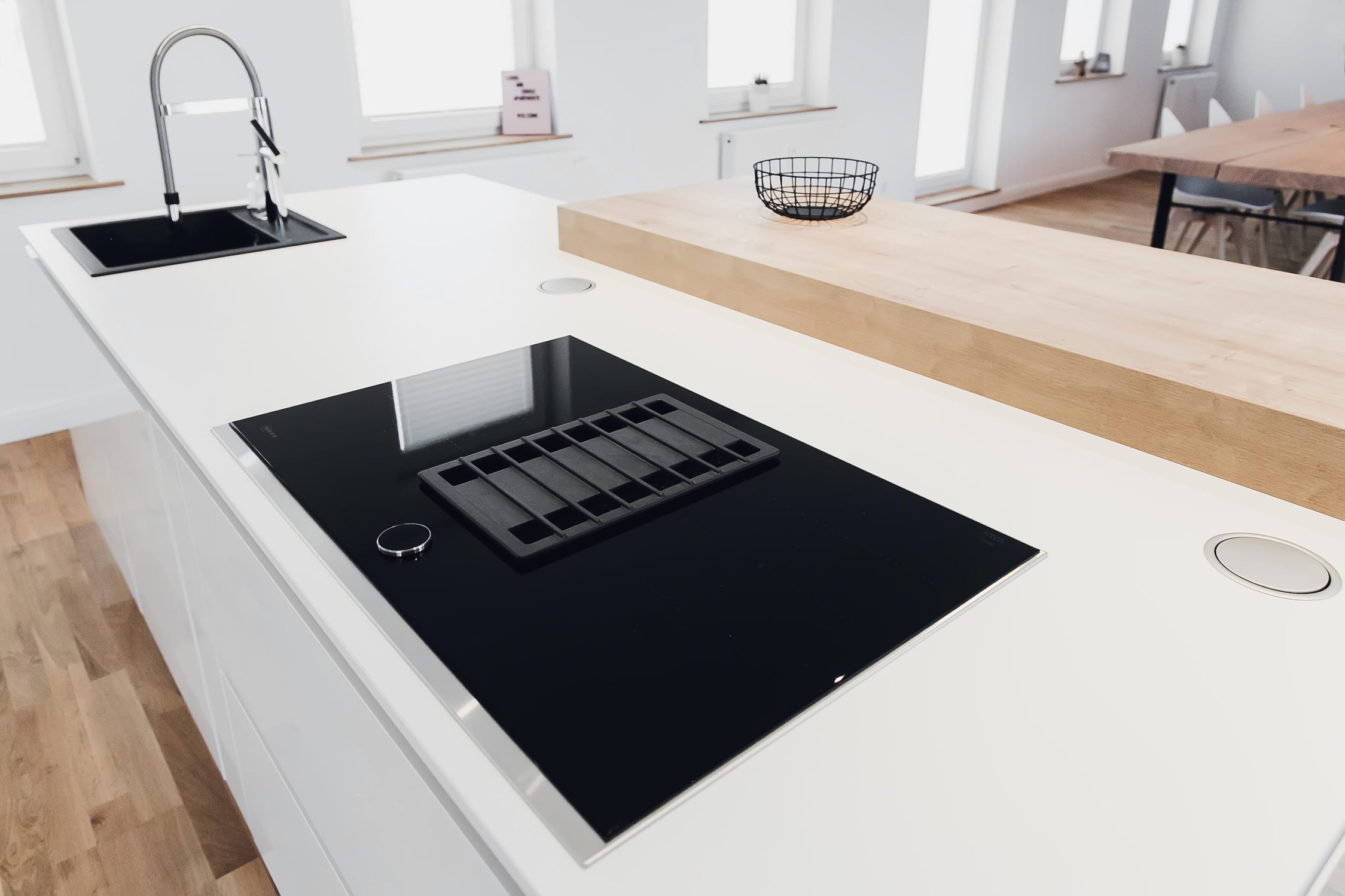 Weiße Kücheninsel mit schwarzem Kochfeld, Spüle und Holztresen