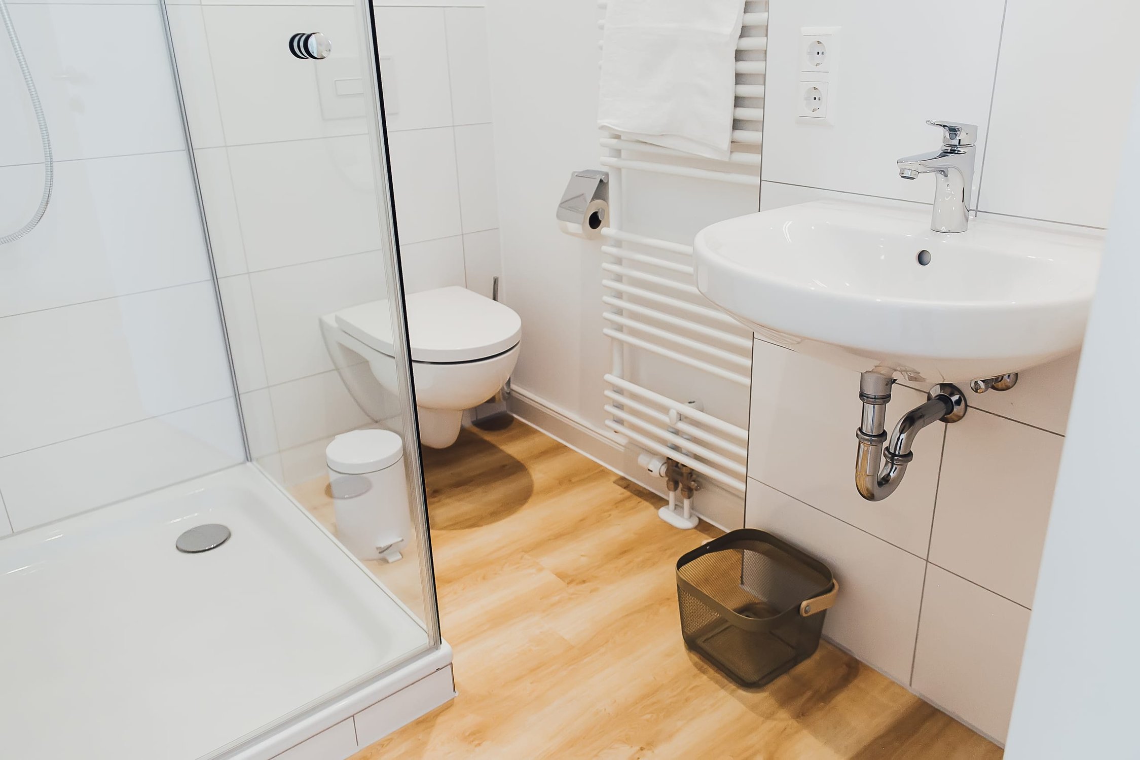 Modernes Badezimmer mit Dusche, Toilette und Waschbecken, hellem Holzfußboden