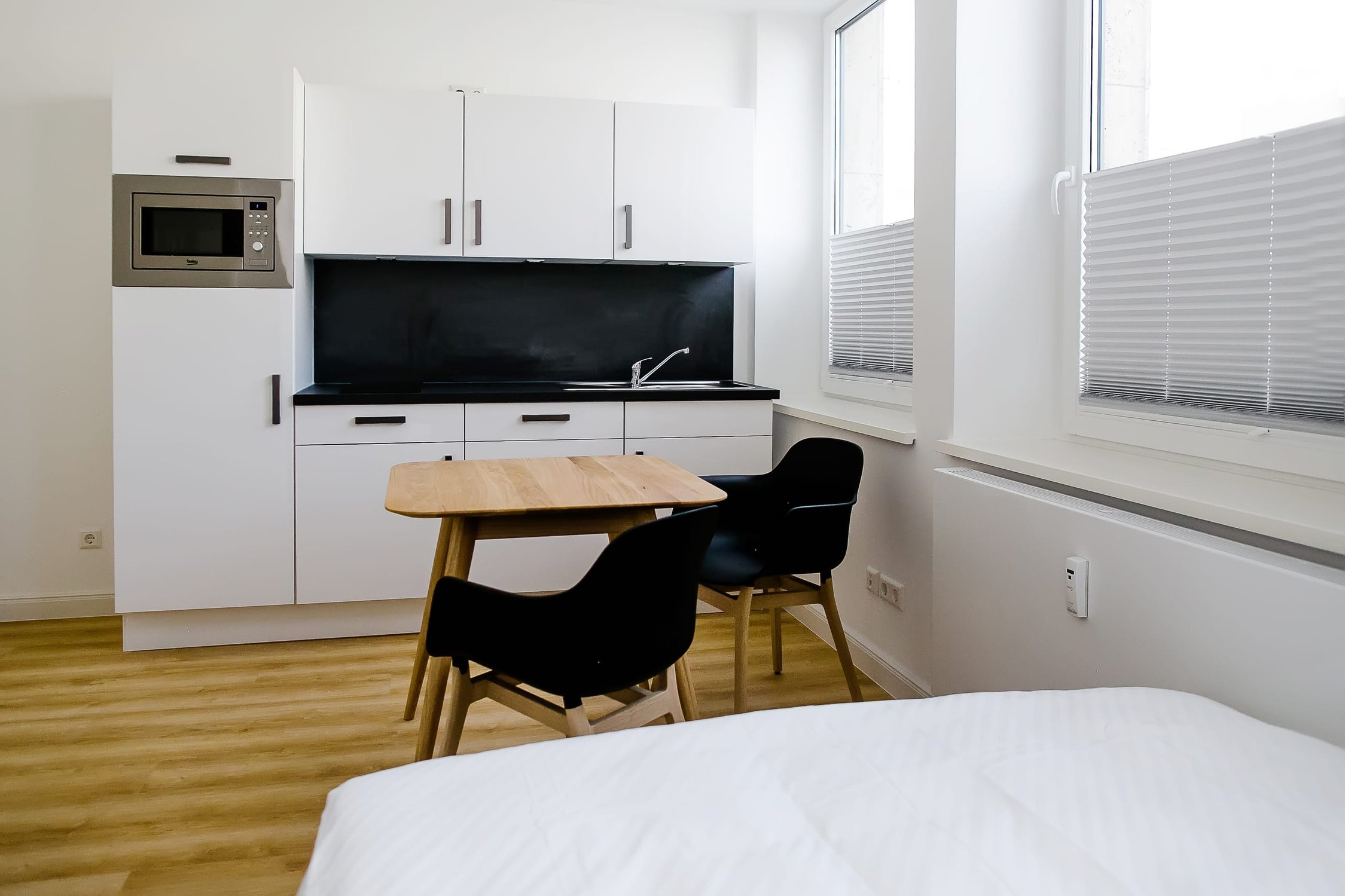 Helles Studio-Apartment mit Küchenzeile, Esstisch für zwei Personen und Fenster mit Jalousien