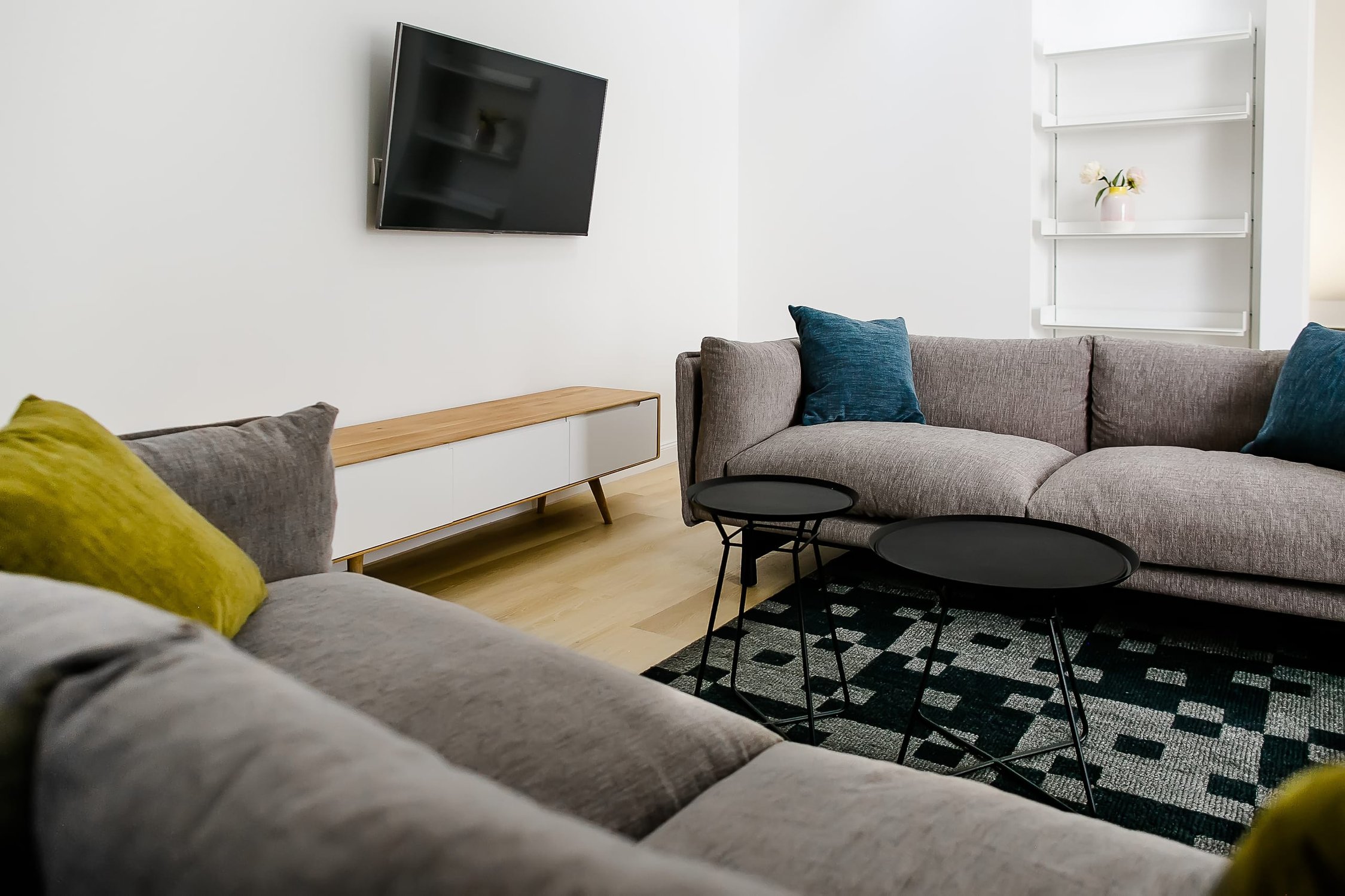 Helles Wohnzimmer mit Ecksofa in Grau, Fernseher und Couchtischen auf Teppich