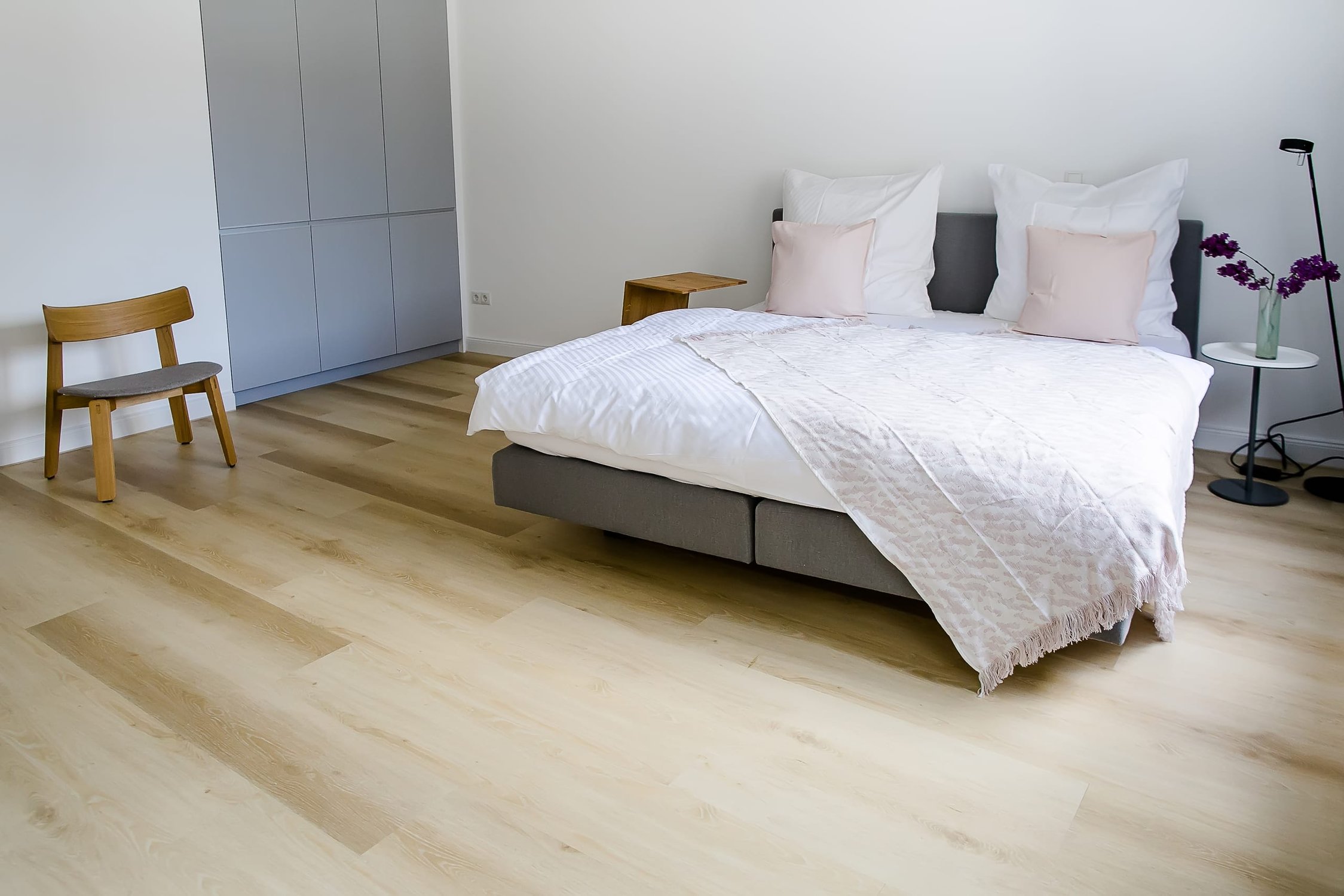 Schlafzimmer mit weißer Bettwäsche, schwimmendem Bett und hellbraunem Holzboden